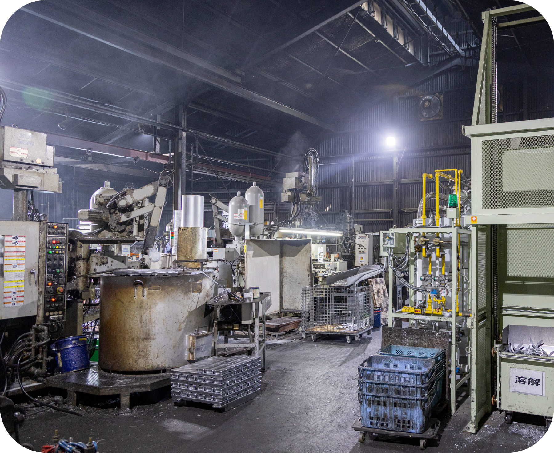 Interior of a metalworking factory floor with heavy machinery, control panels, and hazy air.
